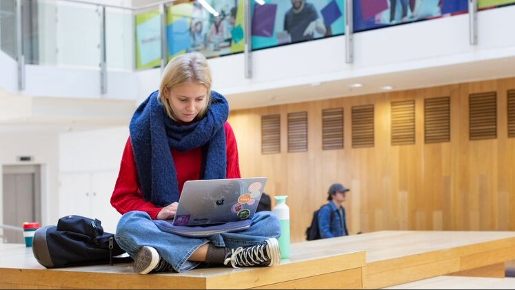 Girl sat cross legged working on a laptop