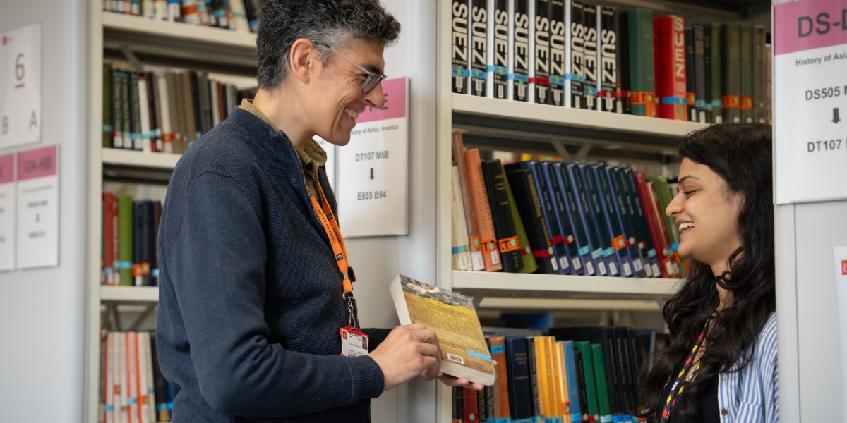 A member of Library staff helping a student in the book stacks